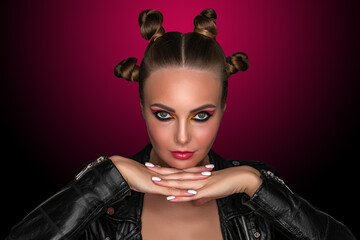 Portrait of a young sassy girl with blond hair in the studio on a pink background.