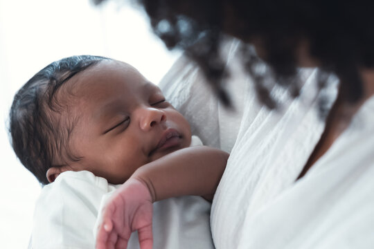 Close Up Portrait Of Cute African American Newborn Infant Baby Lying In Mother's Arms At Hospital. Black Mother Hand Lulling Little Child To Sleeping. Child Care, Newborn Baby Boy Or Girl. New Life