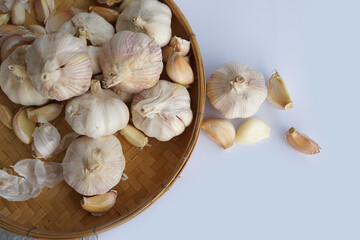 Garlic in a bamboo basket on a white background It is a medicinal plant in Thai kitchens used as an ingredient in food. It has a pungent odor and a spicy taste. It can be eaten both fresh and cooked.