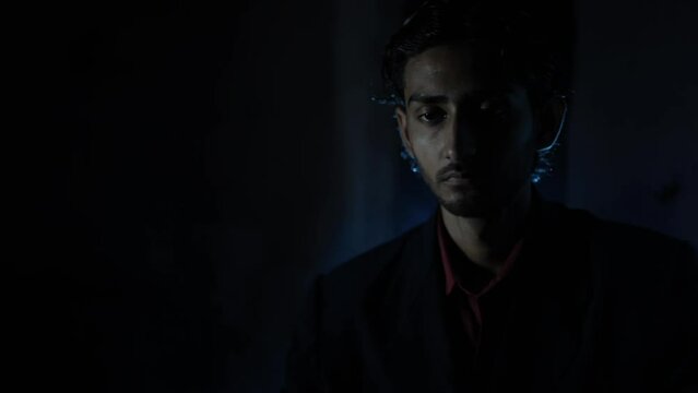 Close-up footage of a man in a blue suit sitting in a creative lighting set, High-quality production HD stock footage.