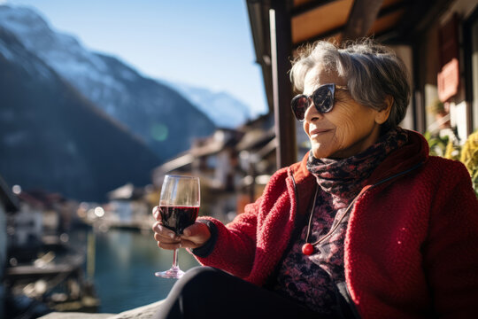Beautiful senior woman drinking wine in small Austrian town in winter. Elderly lady having a good time travelling to Europe on sunny winter day.