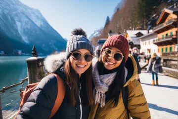 Foto op Canvas Beautiful Asian traveler couple with backpacks exploring small Austrian town at winter. Man and woman having a good time travelling to Europe on sunny winter day. © MNStudio