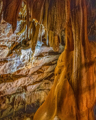 Stalactites et stalagmites avec de belles couleurs ocres dans cette grotte de baume obscure près...