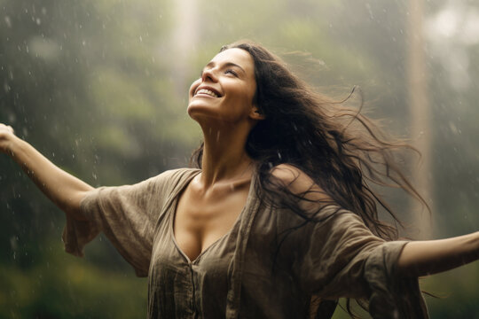 Young woman feeling relieved in beautiful green nature, enjoying the rain, breathing the fresh air with opened arms