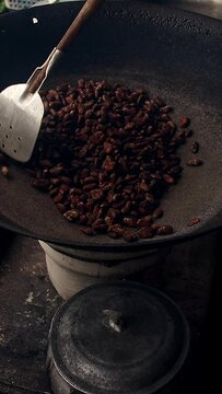 Vertical overhead view of roasting cocoa seeds on a kawa or cauldron, traditional process of making tableya or Filipino handmade chocolate