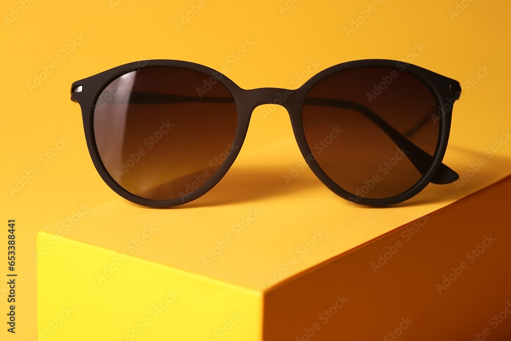 Poster closeup photo of brown sunglasses on a yellow stylish background