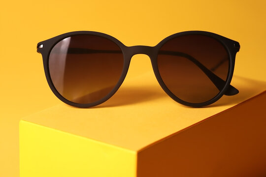 Closeup photo of brown sunglasses on a yellow stylish background