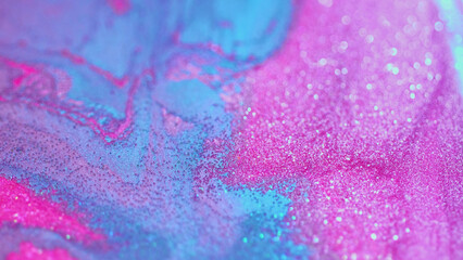 Abstract background. Glitter paint. Shimmering flow. Glamorous sparkling decorative blue and pink ink particles spreading in beautiful acrylic wave.