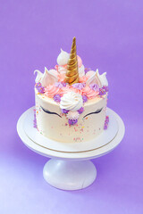 Colorful birthday cake with sprinkles, pink, blue and purple deocrations. Plain background, copy space