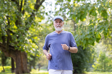 Gray-haired senior man in sportswear running in the park, doing a morning jog, doing sports, keeping fit and leading a healthy lifestyle.