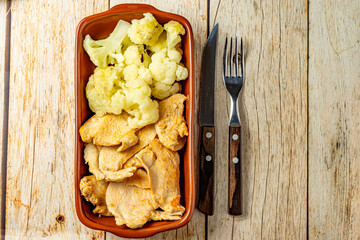 healthy meal, chicken and cauliflower, on a bowl over wooden table
