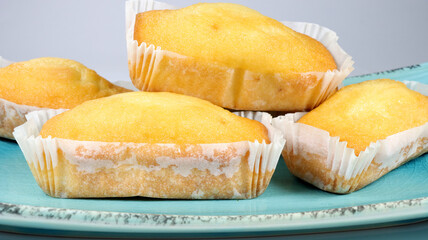 closeup of numerous plumcakes on a tray, white background 