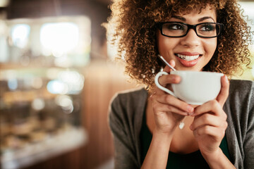 Young African American woman enjoying a cup of coffee alone in a cafe or bar