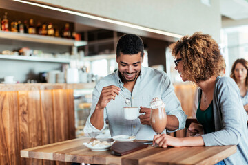 Young African American couple having coffee together while on a date in a cafe or bar