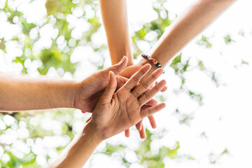 image from below of a group of unrecognizable friends from the lgbt community joining hands...