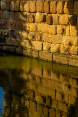 Evening sunlight illuminating the wall of the Roman bridge in Mérida over the Guadiana River, with...