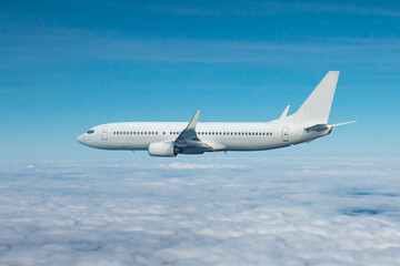 White passenger airliner flying in the air above the clouds