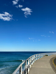 Wooden bridge over the sea. Boardwalk near the blue turquoise ocean, waves. Pier in the sea, White fence. - obrazy, fototapety, plakaty