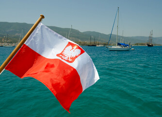 The state flag of Poland on the background of yachts at the anchorage.