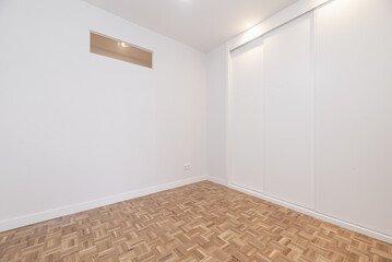 Empty room with a small new built-in wardrobe with white wooden sliding doors, skylight on the...