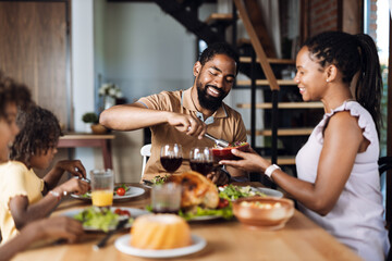 Happy African American family having Thanksgiving dinner at dining table