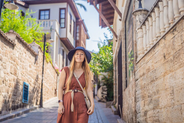 Happy woman tourist on background of old street of Antalya. female tourist traveler discover interesting places and popular attractions and walks in the old city Kalechi of Antalya, Turkey. Turkiye