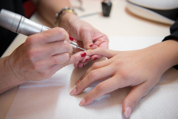 young woman getting a manicure with an Electric Nail Drill in a beauty salon