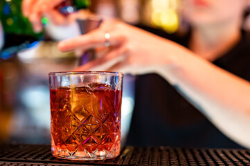 woman hand bartender making negroni cocktail in bar