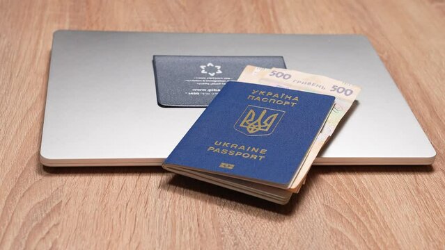 Israeli passport and Ukrainian passport in hands. Shekels and hryvnias, the national currency. Concept: repatriation, change of citizenship, aliyah, absorption basket.