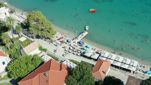 Little restaurant at beach in Croatia. Tourists under sunshade umbrellas