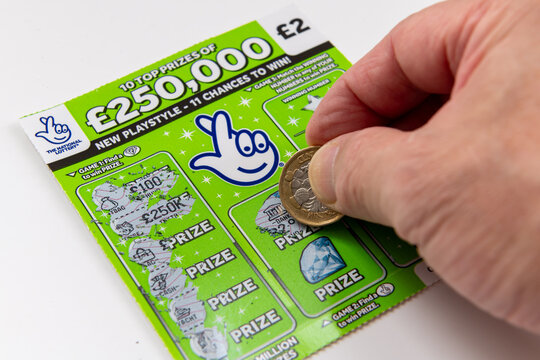London. UK- 09.27.2023. A National Lottery scratch cards isolated in white with a player using a coin to scratch the card.