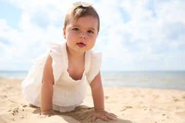 A portrait of a 1 year old caucasian baby girl on the sandy beach on a sunny warm day at Baltic Sea