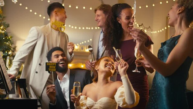Group of friends around piano celebrating with champagne at New Year party together - shot in slow motion