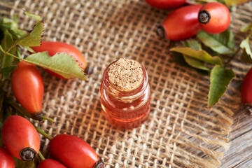 A bottle of rose hip oil with fresh rosehip berries