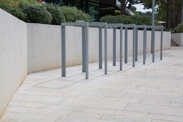 Modern Garden Design and Landscaping: Metal weatherproof bike racks at a sidewalk or promenade made with light paving stones and white concrete walls with integrated green plants