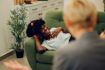 An African American client is lying down on the therapist's bed