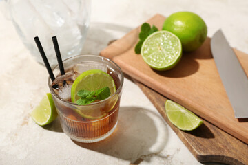 Glass of tasty Cuba Libre cocktail on light background