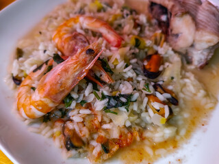 Selective focus on shrimp on top of fish rice and mussels with parsley in blur