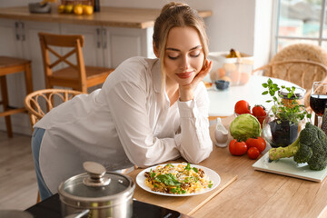 Young woman with tasty pasta in kitchen