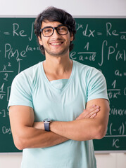 Young male student mathematician in front of chalkboard