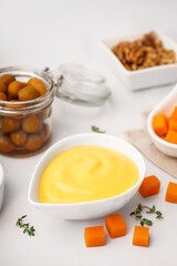 Bowl with tasty cheddar cheese sauce, thyme and olives on white background