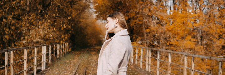 beautiful long-haired woman walks through the autumn streets. Railway, autumn, woman in a coat.