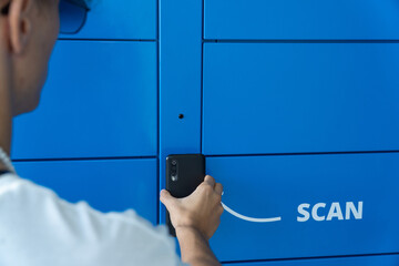 Man scanning a code on the mobile phone to pick up a package from a blue locker. Online shopping, e-commerce and packages concept