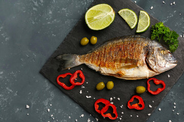 Slate board with tasty grilled dorado fish on grey background