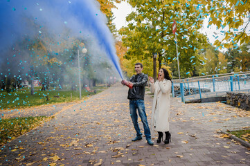 A man hugs a pregnant woman. A man uses a fire extinguisher to determine the sex of his child. Gender party. Happy parents