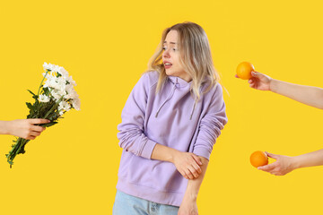 Allergic young woman and female hands with allergens on yellow background