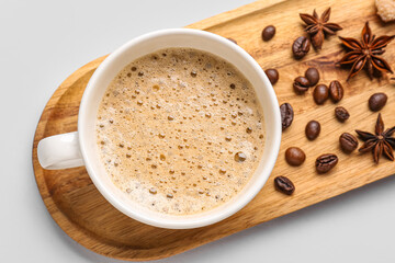 Board with cup of hot espresso and coffee beans on white background