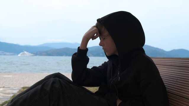 Depression. A young girl in depression sits on the shore of the bay and thinks about suicide.