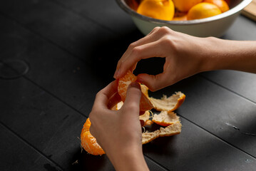 female hands peeling a tangerine over the table