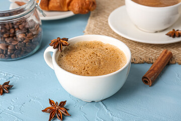 Cups of delicious espresso with coffee beans and star anise on blue background, closeup